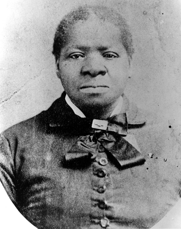 Black and white portrait of Biddy with buttoned dress and ribbon around neck. Her hair is pulled back.