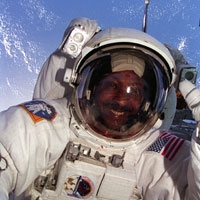 selfie of Winston Scott wearing a space suit with Earth behind him