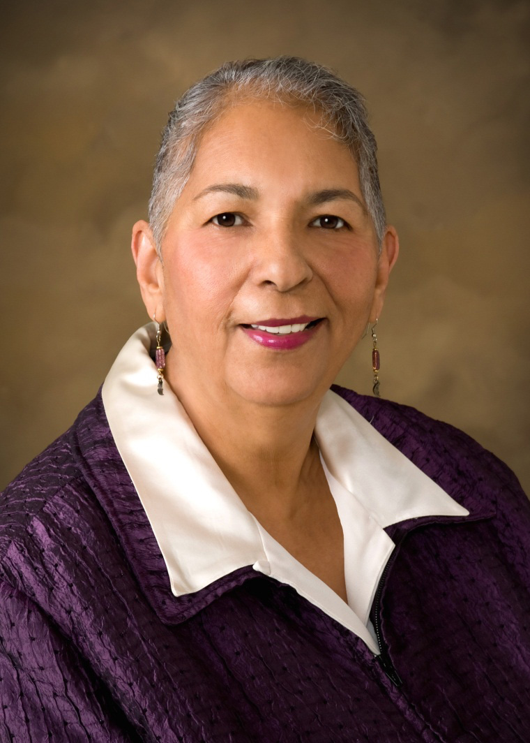 Johnson posing, wearing earrings and a purple coat