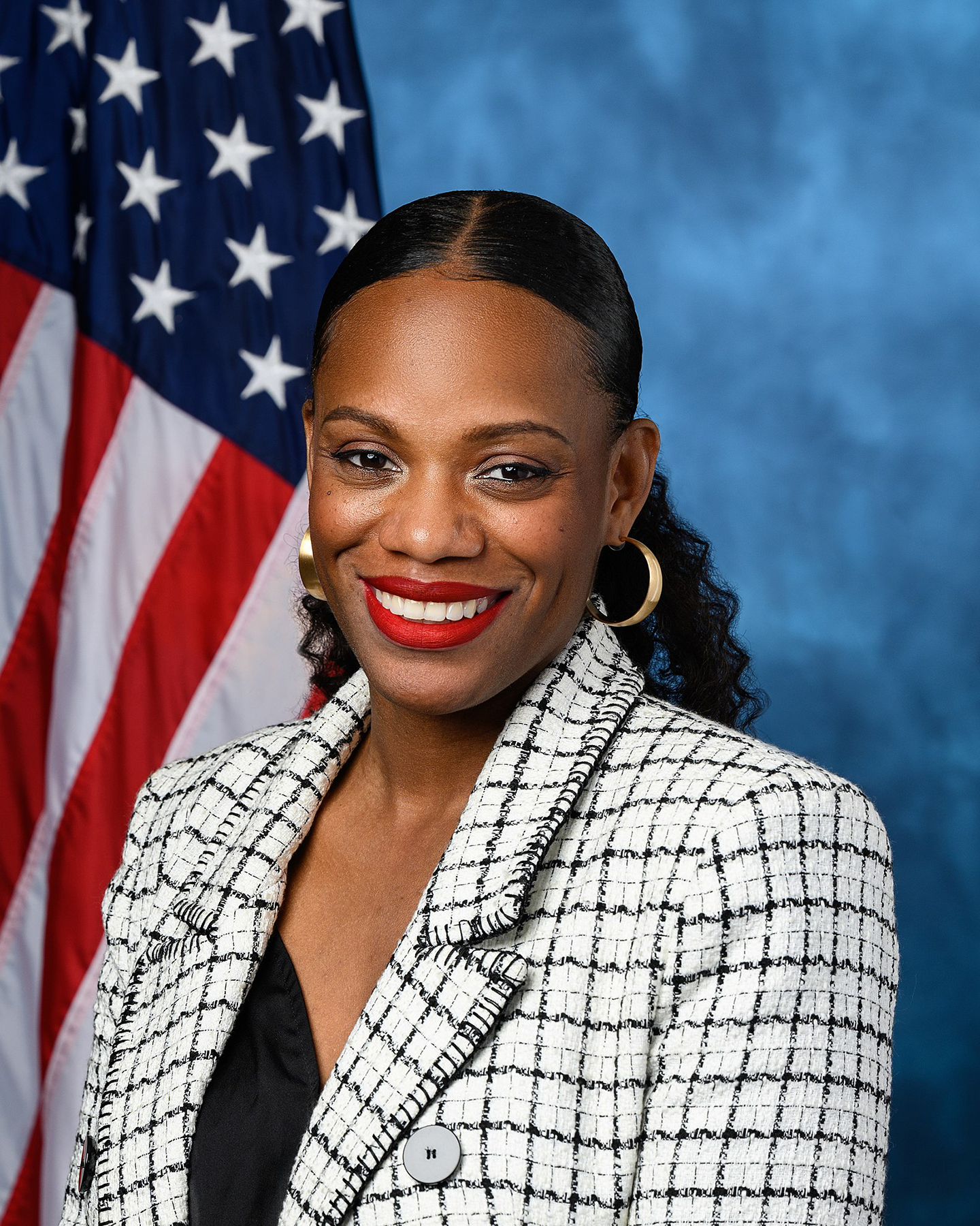 Pennsylvania State Representative Summer Lee posing in front of American flag|>Pennsylvania State Representative Summer Lee speaking behind a podium and holding a microphone