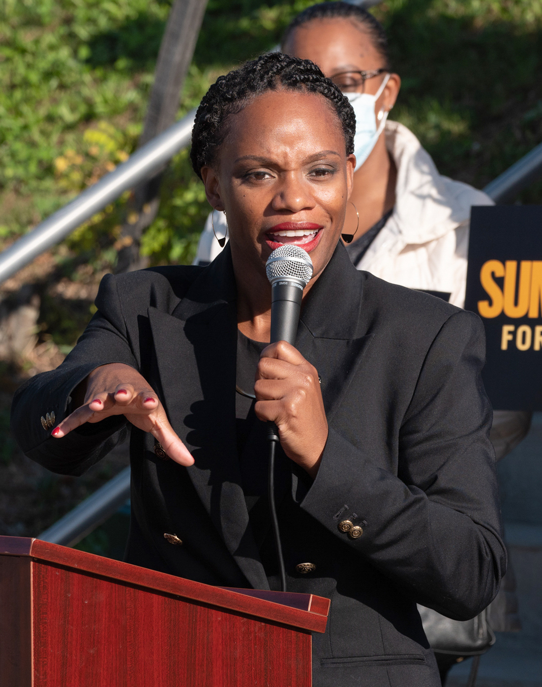 >Pennsylvania State Representative Summer Lee speaking behind a podium and holding a microphone