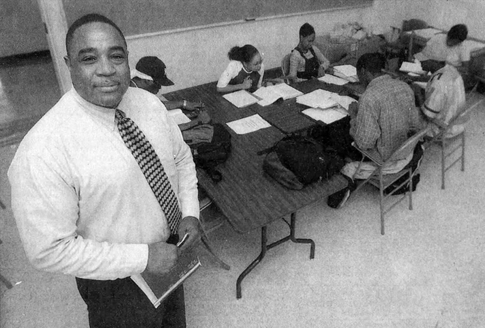 Overhead shot of Weatherby smiling while students with open textbooks sit at a desk in the background|Dennis Weatherby with Cascade products