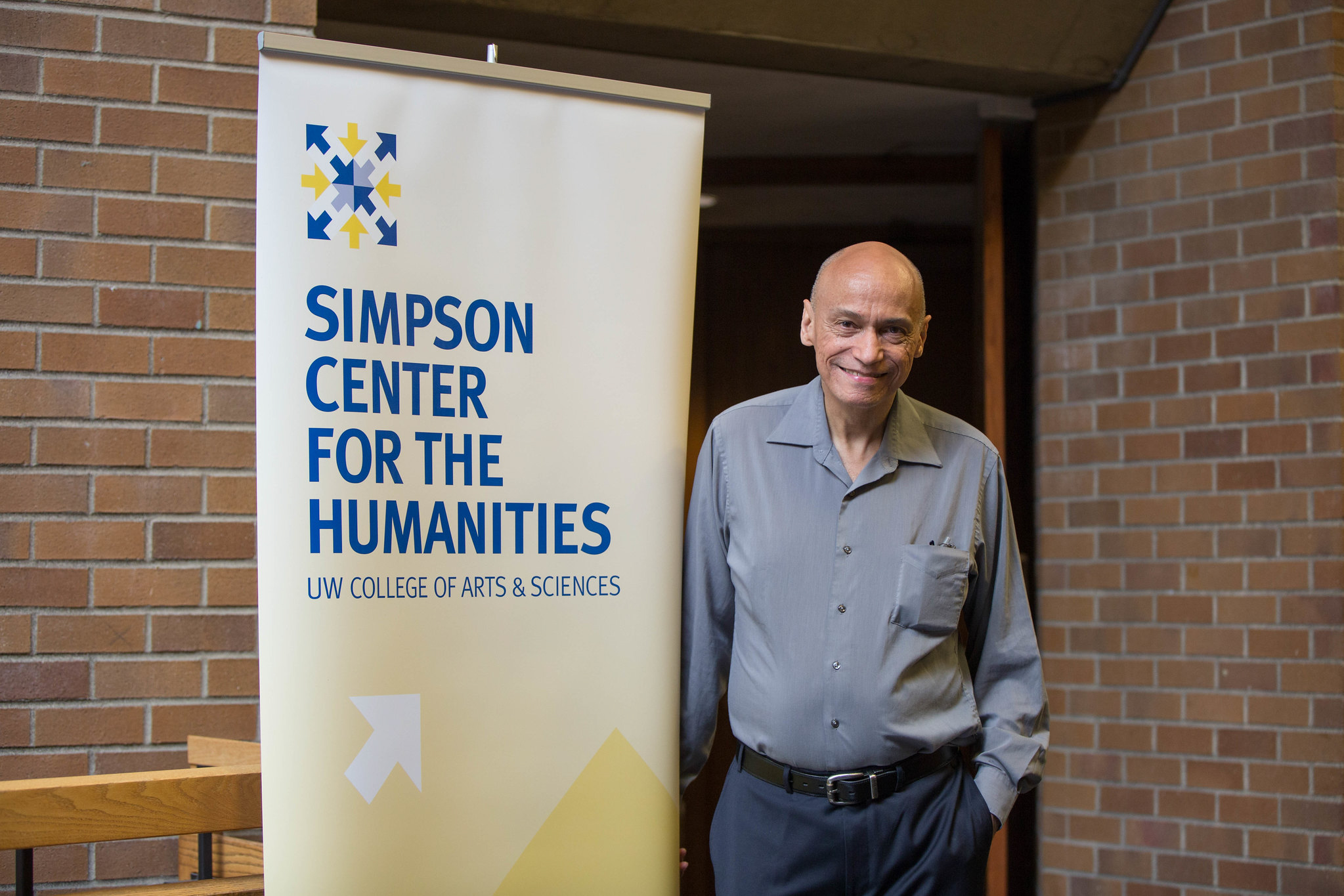 Mills standing in front of a banner for the University of Washington's Simpson Center for the Humanities|Mills lecturing in front of a crowd