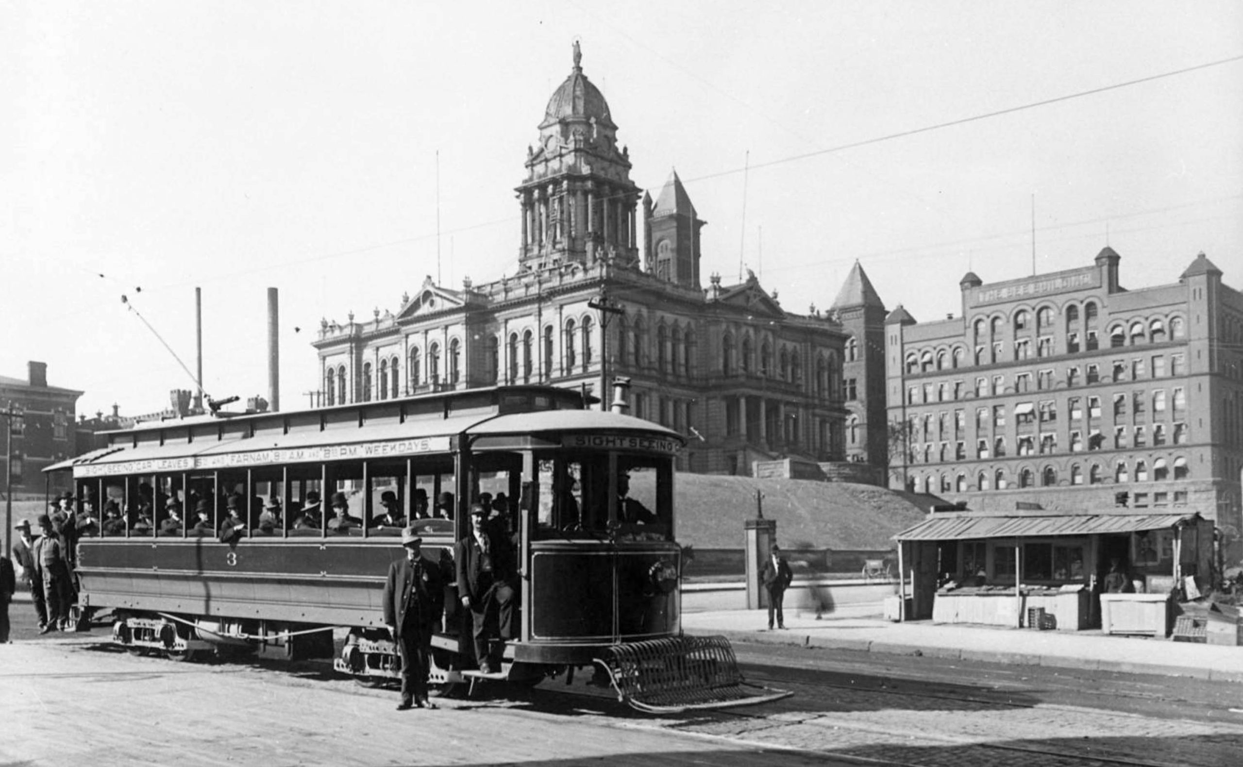 Black and white street-view of a streetcar in the foreground