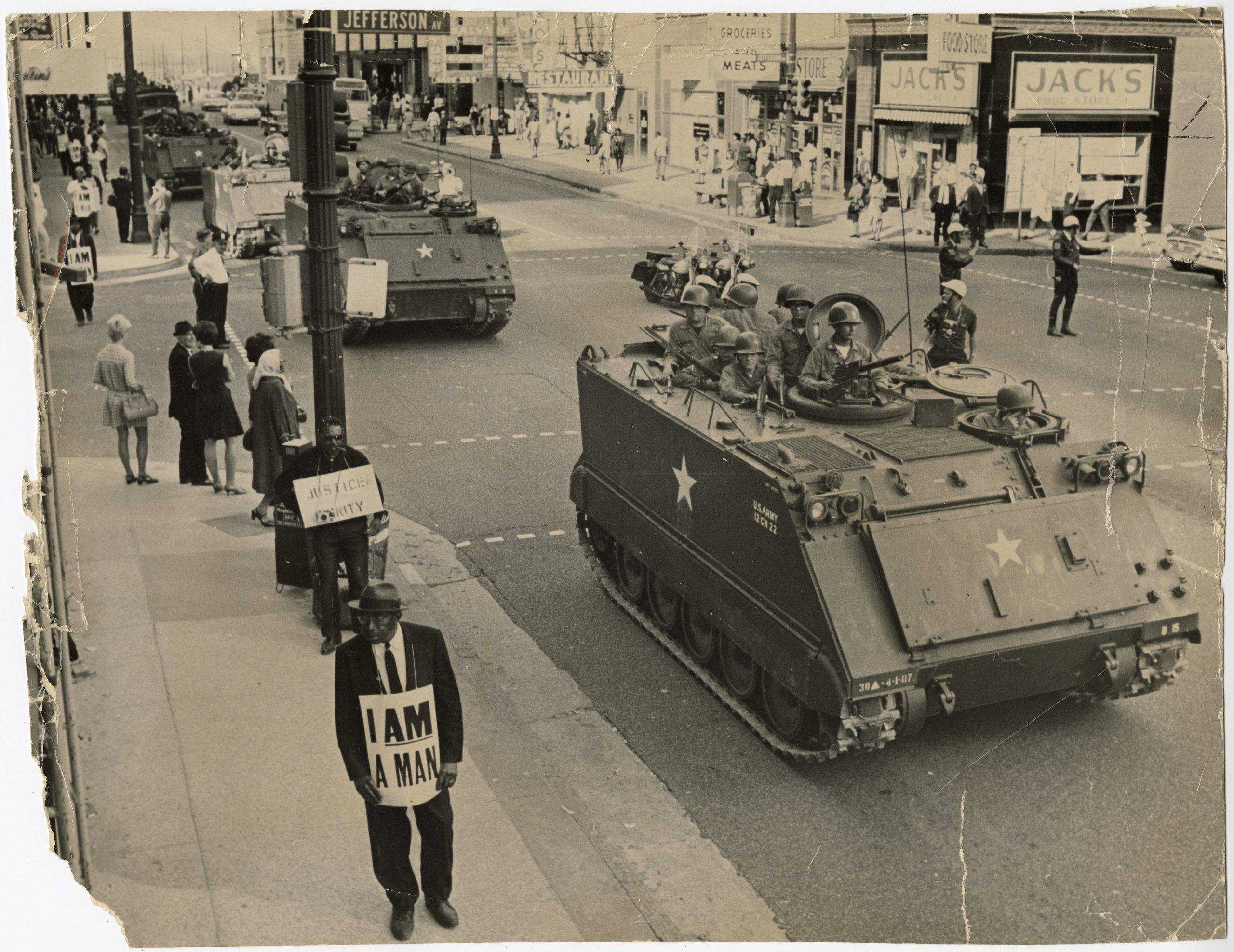 Protesters carrying signs march while National Guardsmen patrol on Main Street at the corner with Jefferson Avenue in Memphis, Tennessee, on March 31, 1968.