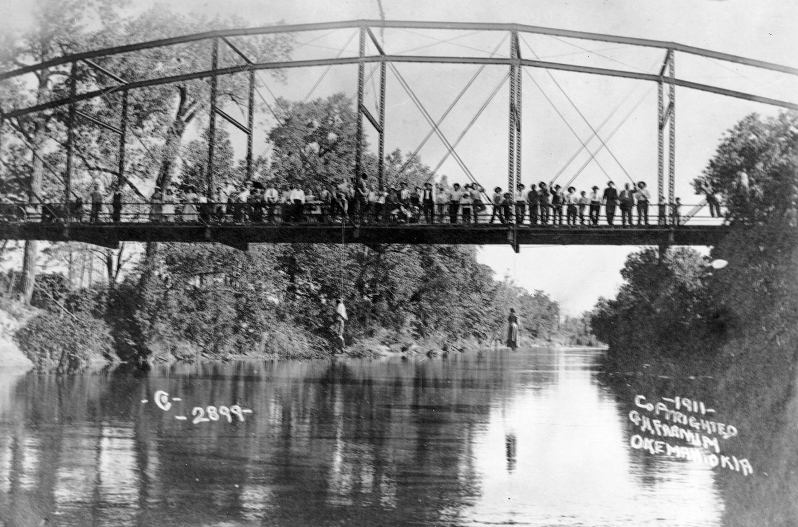 Group of families on a bridge with the hanged bodies of Laura and Lawrence Nelson over the North Canadian River